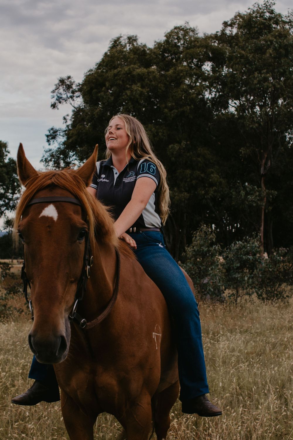 Girl laughing on her horse in a paddock.