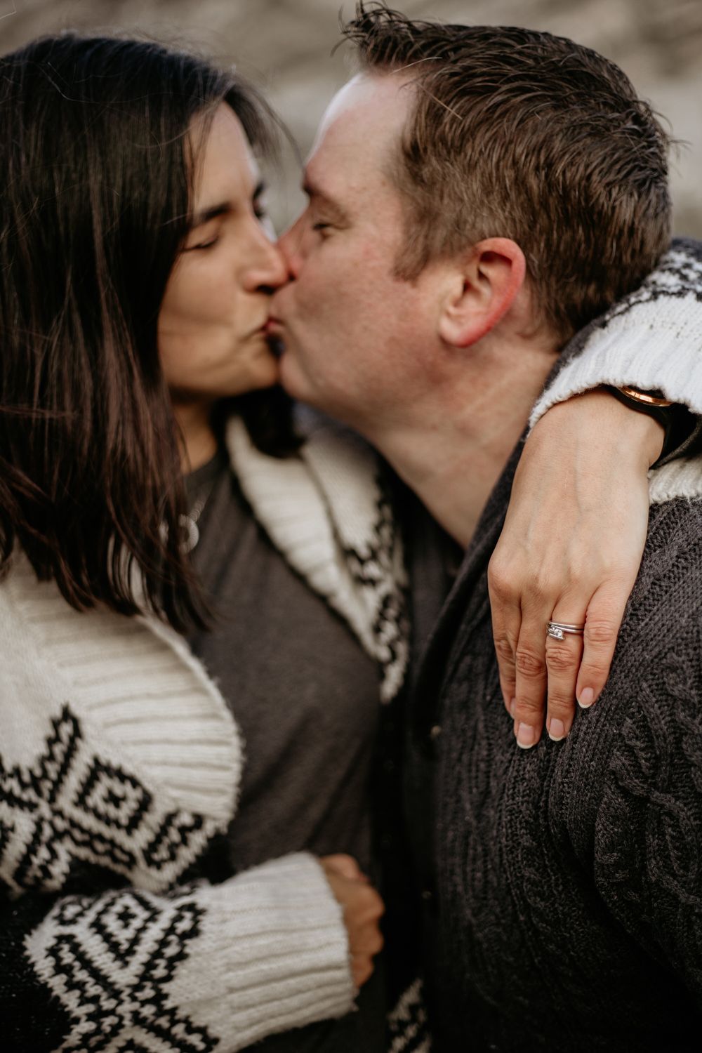 Close-up of couple in matching winter sweaters sharing a tender kiss.