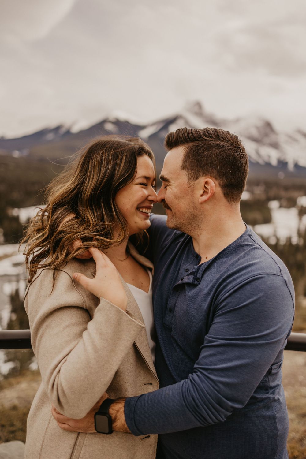 Romantic couple embracing with snow-capped mountains in background.
