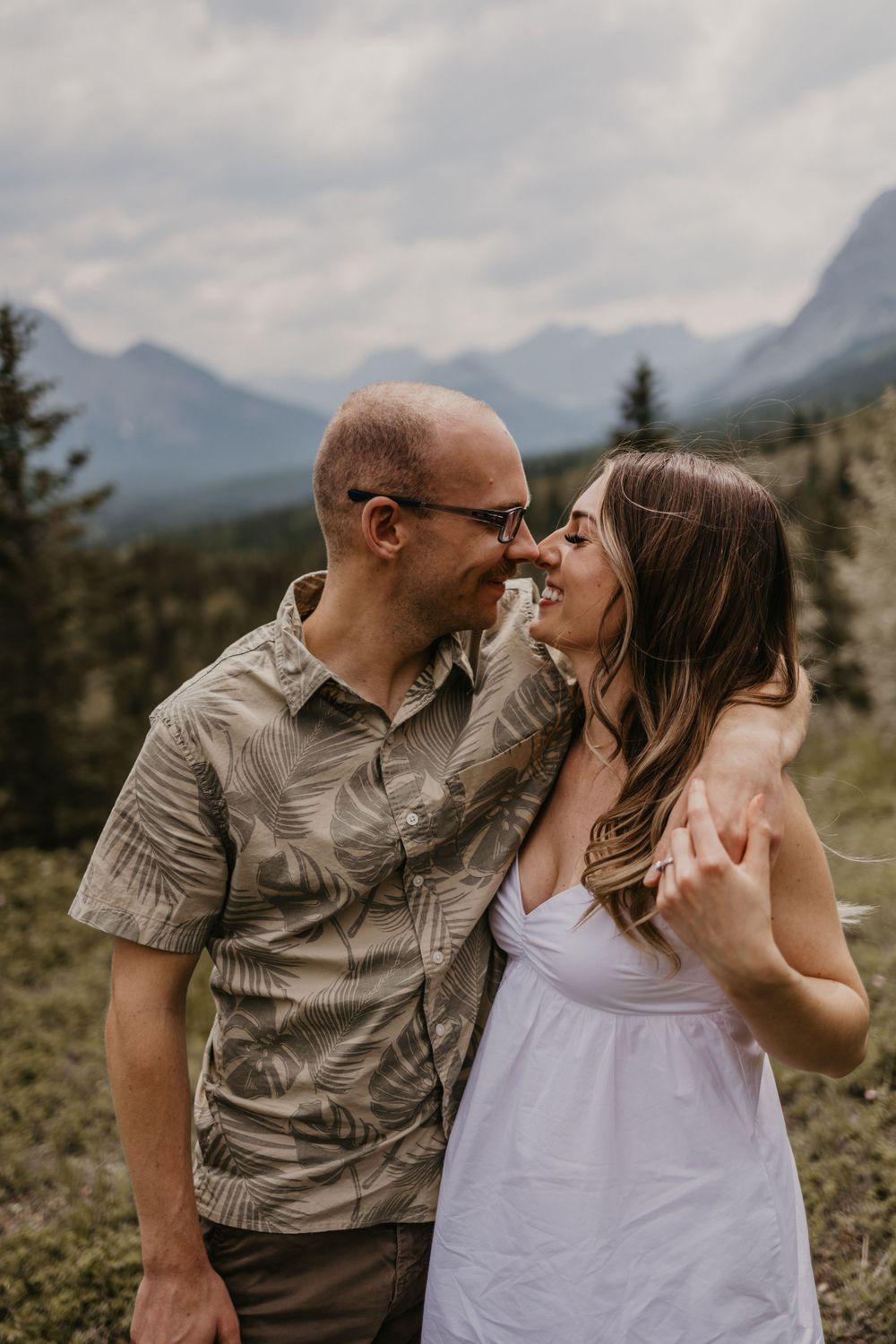 Intimate couple portrait with mountain vista and evergreen forest background.
