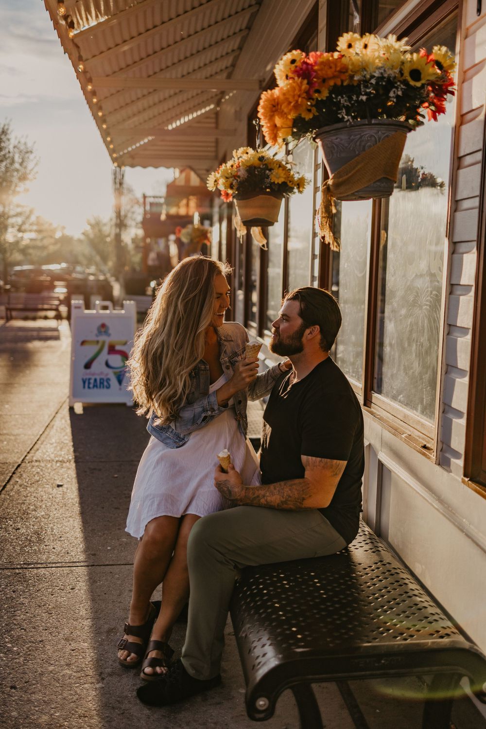 Romantic sunset moment outside storefront with hanging flower baskets.