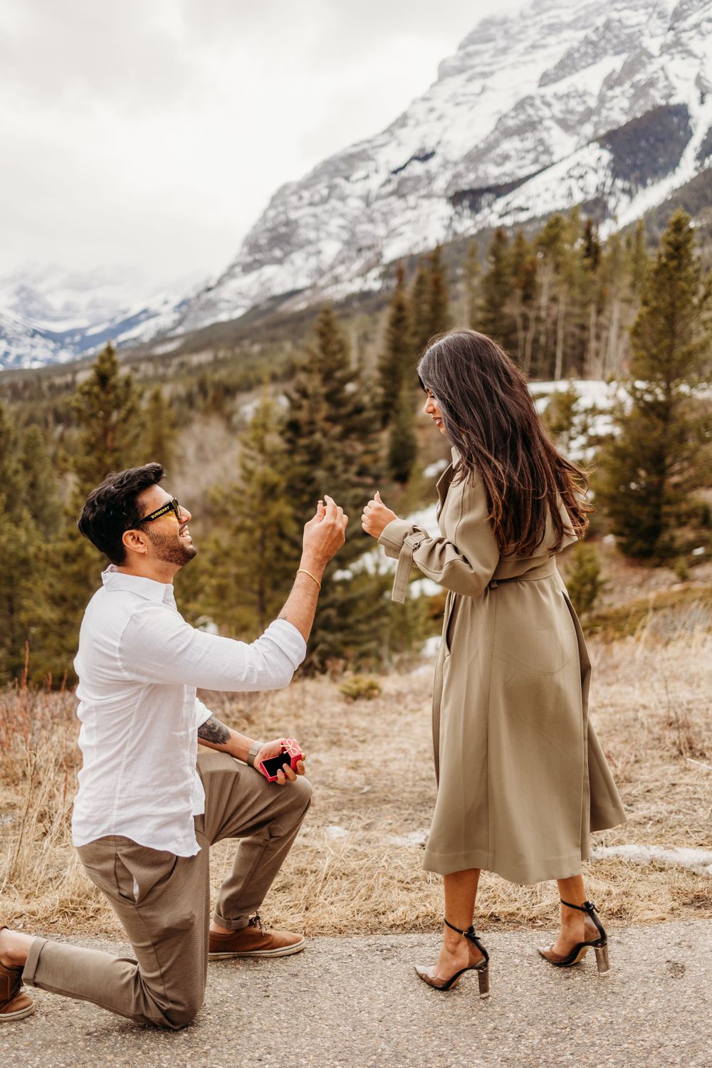 Surprise proposal moment against backdrop of snowy mountain landscape.