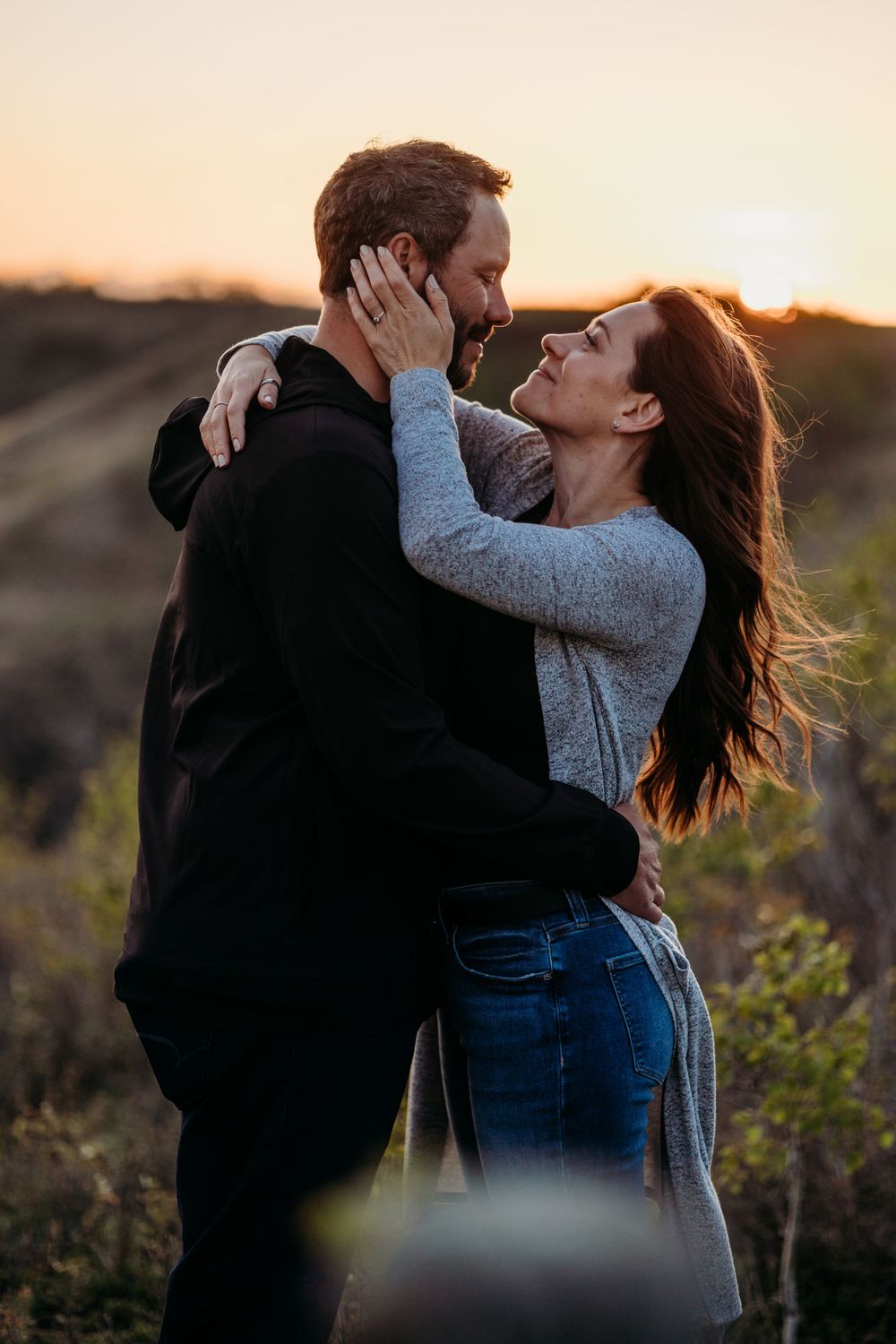 Intimate couple sharing tender moments during golden hour in a natural outdoor setting.