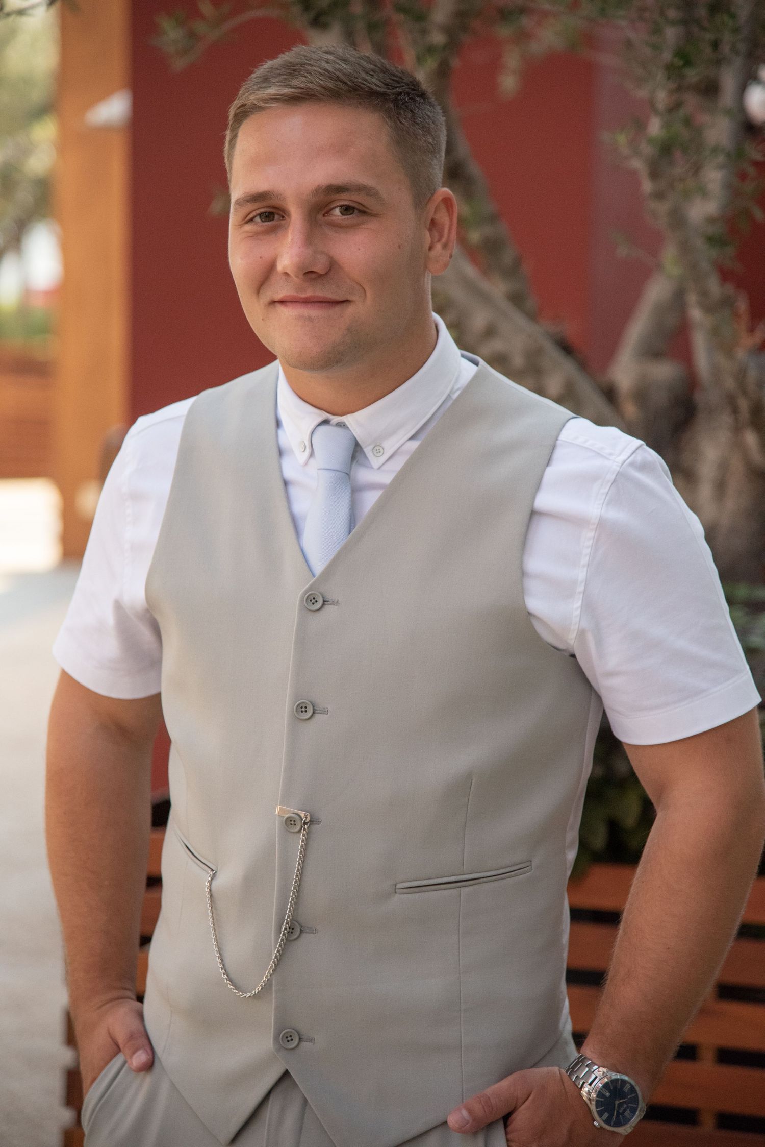Person in formal white shirt and grey vest at outdoor venue.