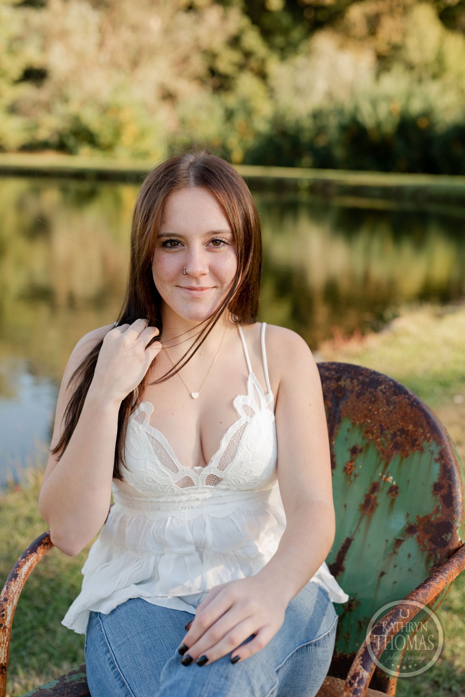 Portrait on vintage metal chair by pond with natural autumn lighting.
