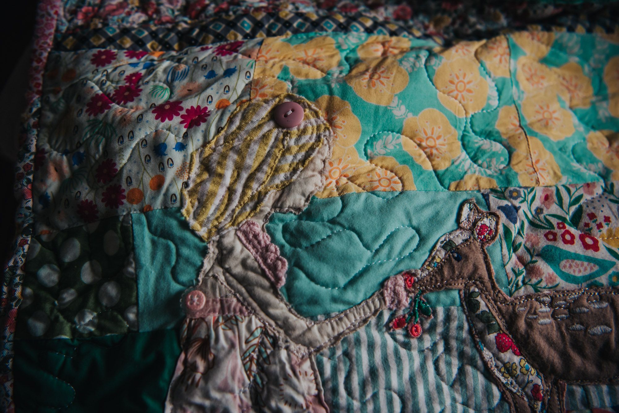 Custom applique of a little girl made out of old baby clothes on a custom memory quilt.