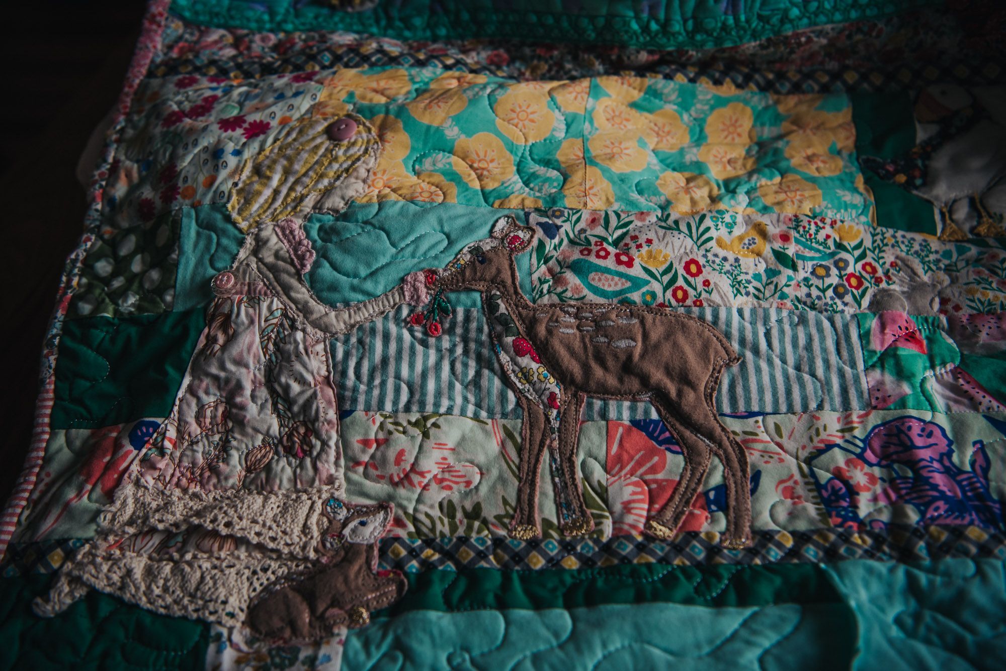 Applique of al little girl in a dress feeding a deer made from baby clothes on a memory quilt.