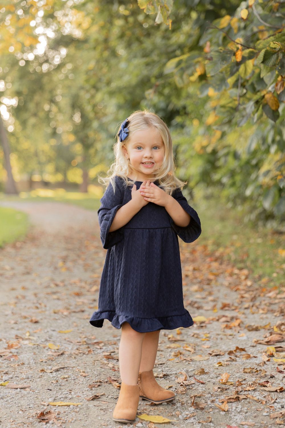 3 year old girl posing for a photo in a blue dress and tan boots at dodge park