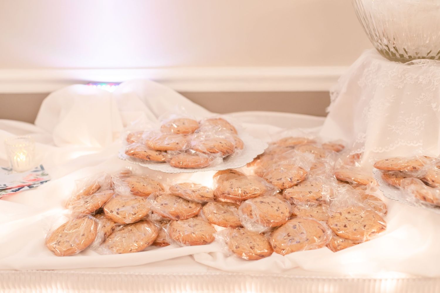 Array of freshly baked cookies displayed on white plates at a wedding dessert table.