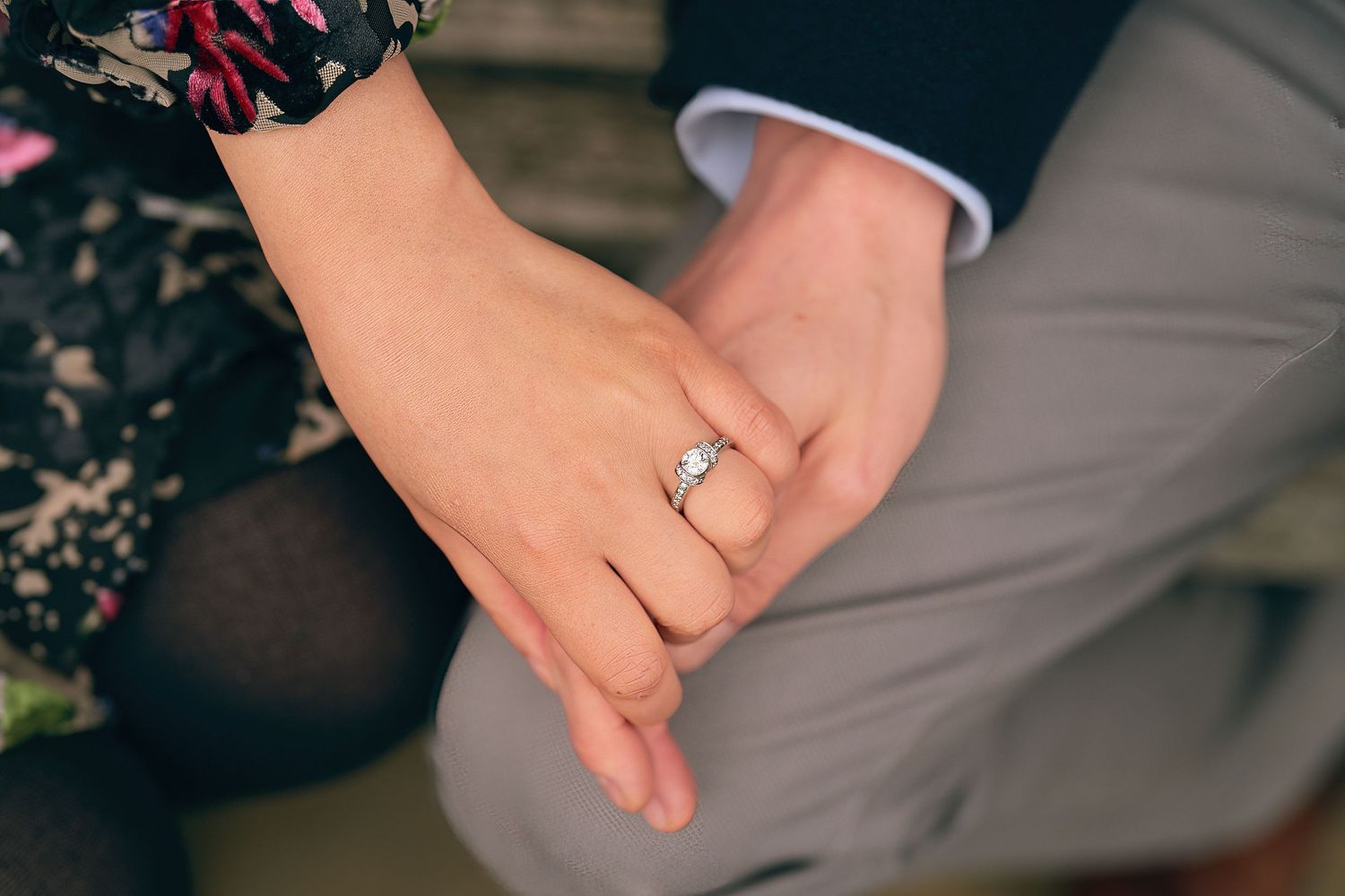 Close-up shot of hands wearing wedding rings against a dark background.
