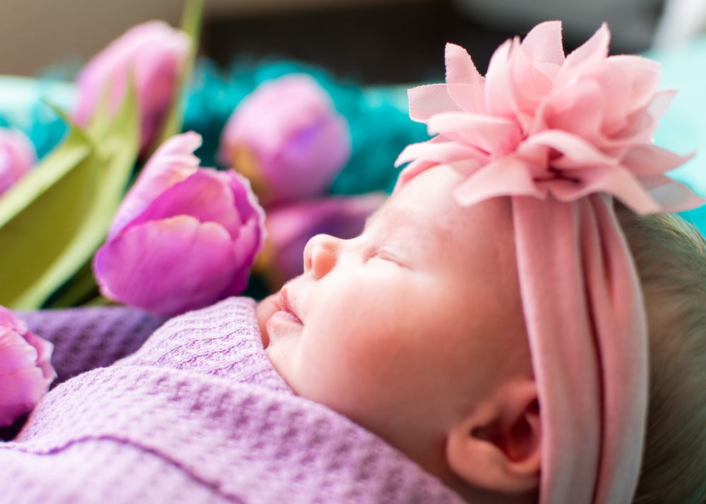 newborn daughter with pink flower headband and purple wrap