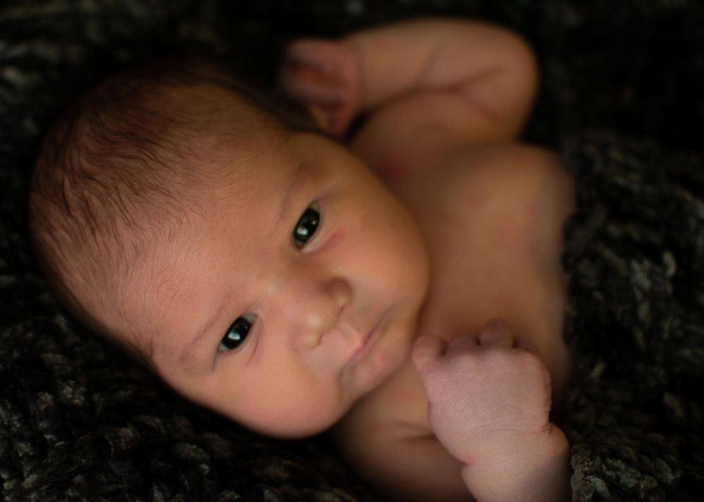 newborn baby, black background, awake