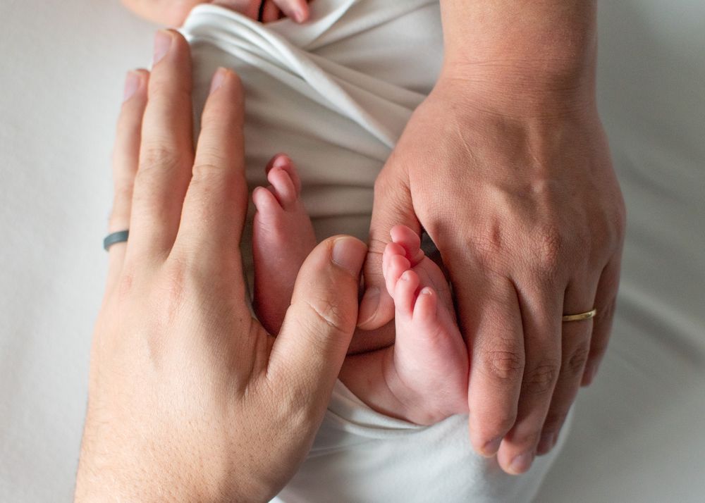 mom and dad's hands holding newborn's feet