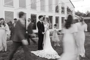 Wedding guests gather outside a white building in a blurred black and white motion effect photograph.