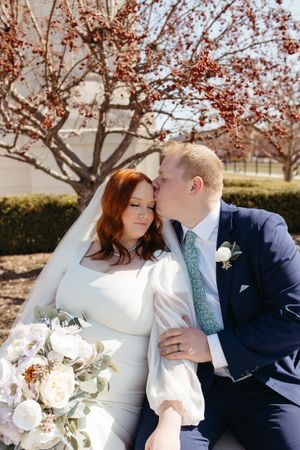 A romantic wedding moment captured under blooming cherry trees during springtime.