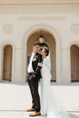 A couple shares a playful and romantic moment under an arched temple entrance.