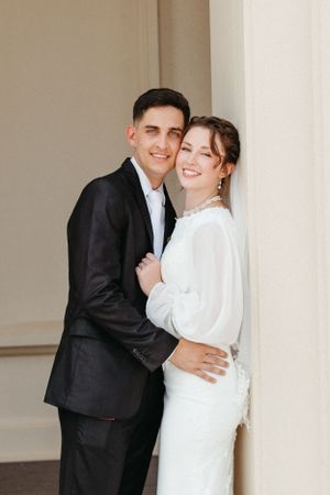 Elegant couple in formal wear share loving moment in archway.