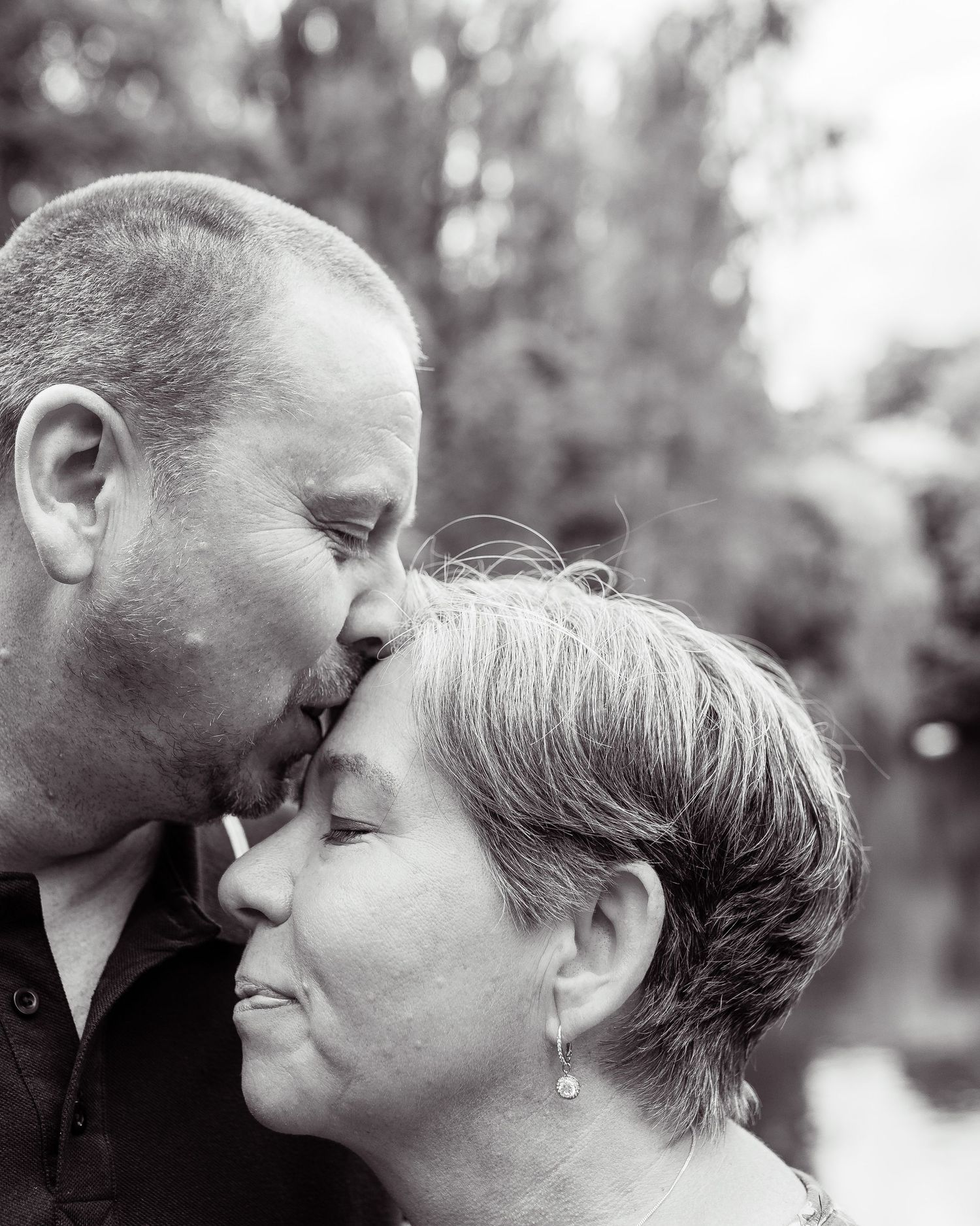 An intimate black and white portrait of a couple sharing a tender moment.