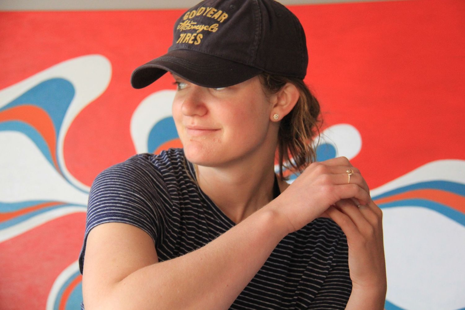 Photographer in a striped shirt and baseball cap sitting against a vibrant red background.