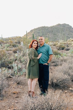 Tucson family photo of a couple standing together in desert landscape with mountains and native plants
