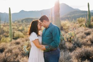 Tucson couples portrait of a man and woman holding each other in the desert with saguaros and mountain views at sunset.