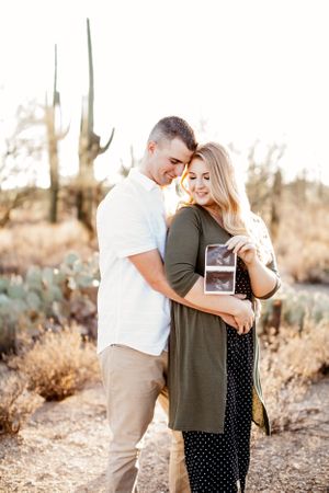 Tucson couples portrait of a man and woman embracing in the desert surrounded by saguaros and golden light.