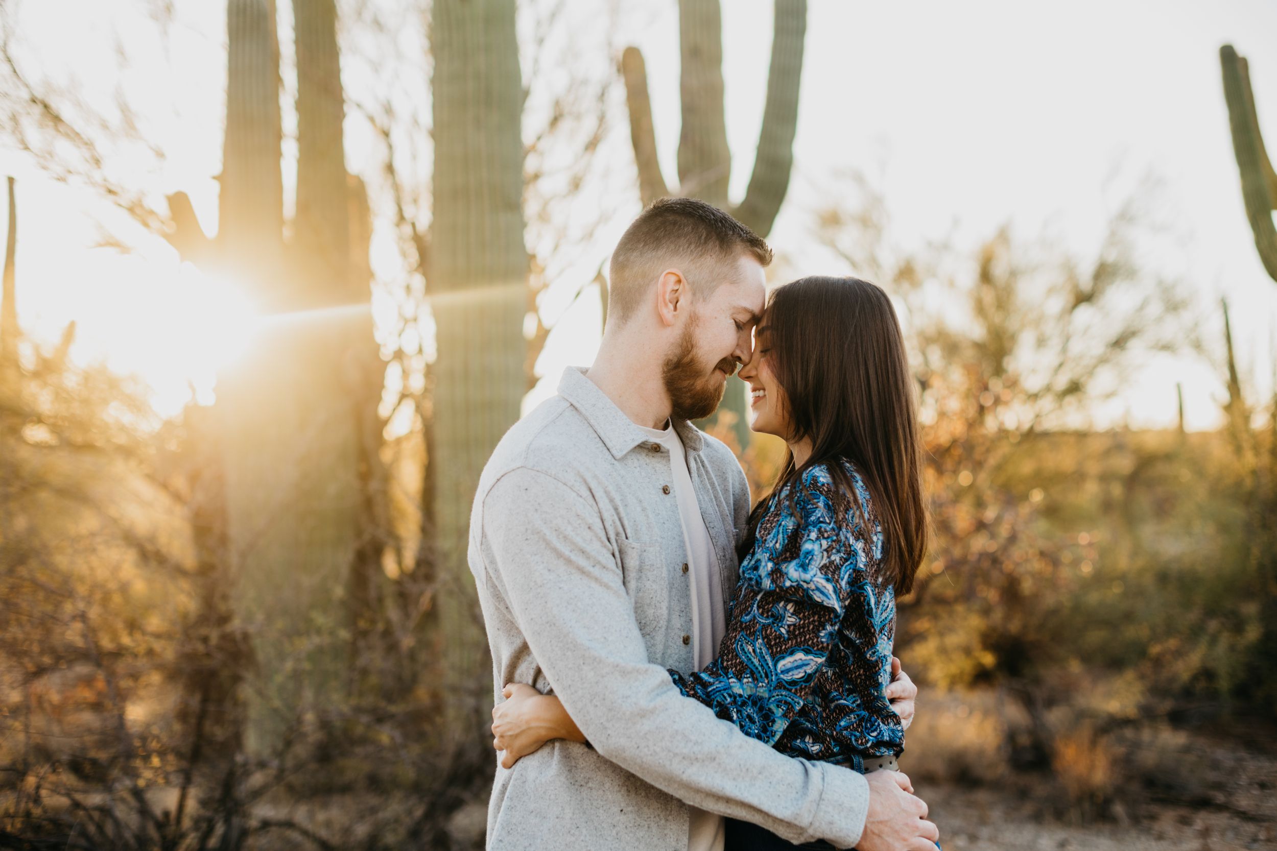 Tucson couples photo of a man and woman embracing at sunset with golden desert light shining through the trees.