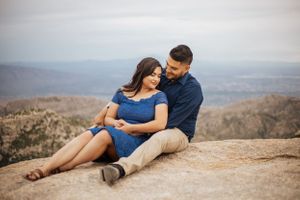 Tucson couples session featuring a couple sitting on a rocky mountaintop with desert views.