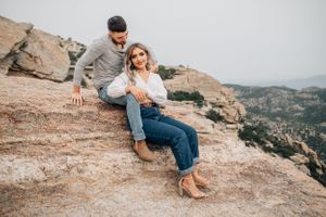 Tucson couples photo of a man and woman sitting on a rocky overlook with mountain views at Mount Lemmon.