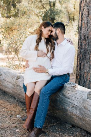 Sweet Tucson couples portrait of a couple sitting closely on a log, surrounded by warm golden desert tones.