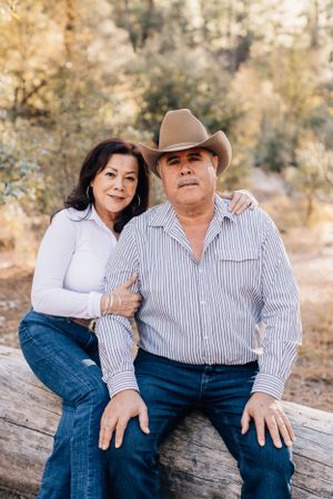 Tucson couples portrait of a man and woman sitting together on a log in a warm, golden outdoor setting.