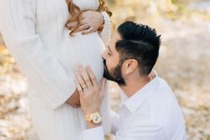 Tucson maternity photography featuring a father kissing his partner’s pregnant belly in soft natural light.