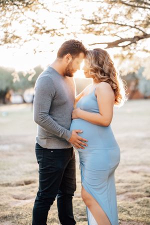 Tucson maternity portrait of a couple holding the baby bump outdoors in soft golden light.