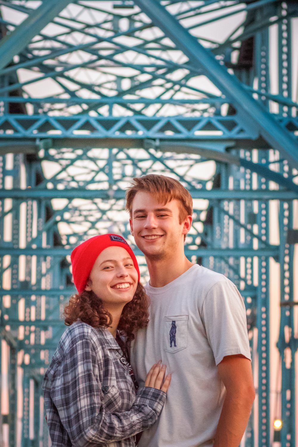 Couple sharing an intimate moment on a blue steel bridge during golden hour.