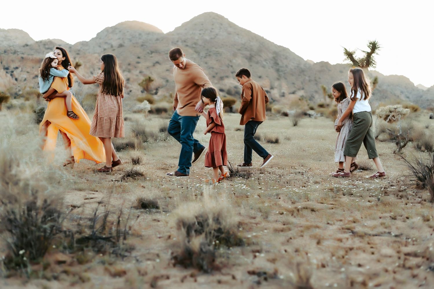 Group dancing and celebrating in desert landscape with mountains in background.