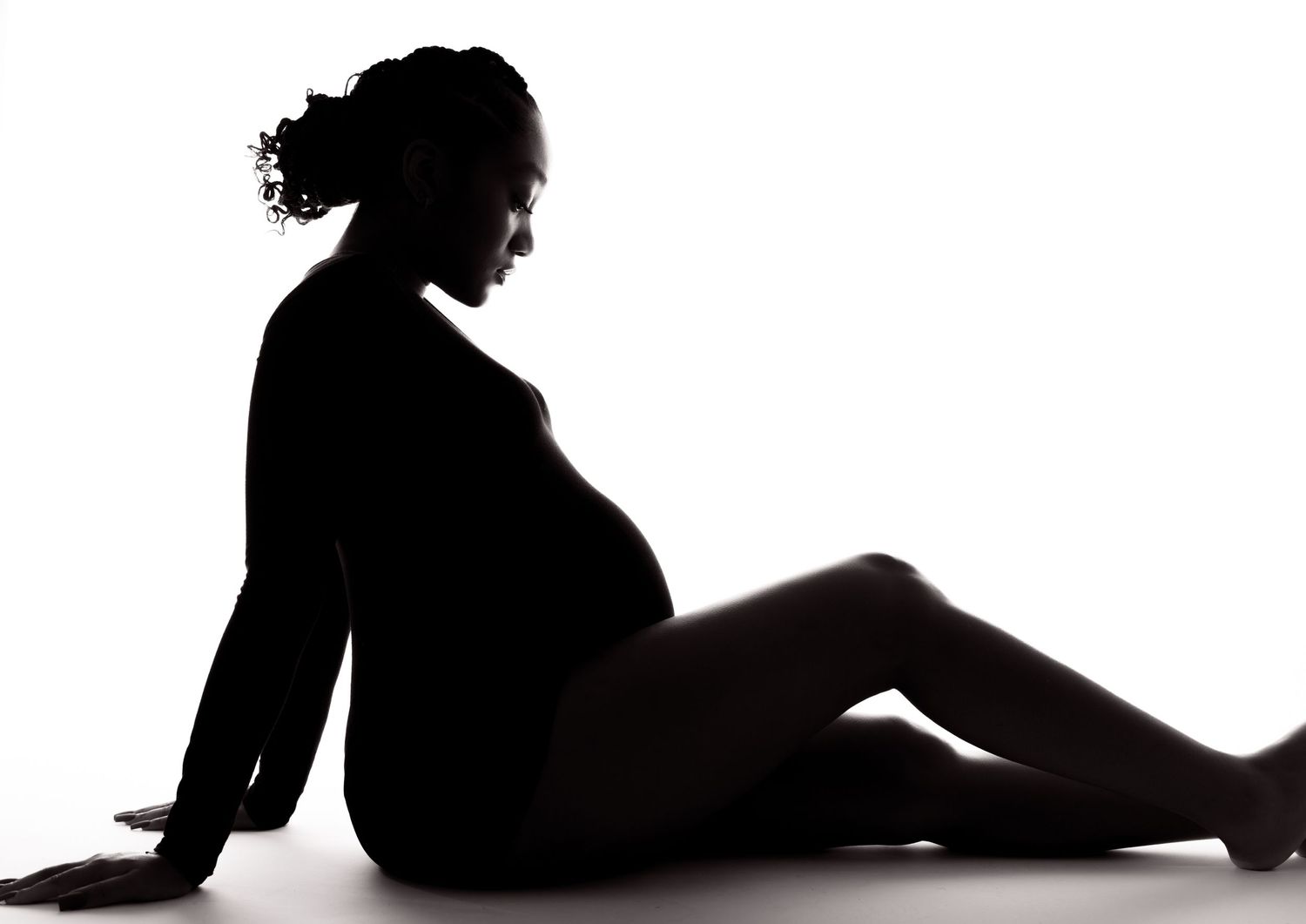 Side profile silhouette of pregnant woman resting in relaxed seated position.