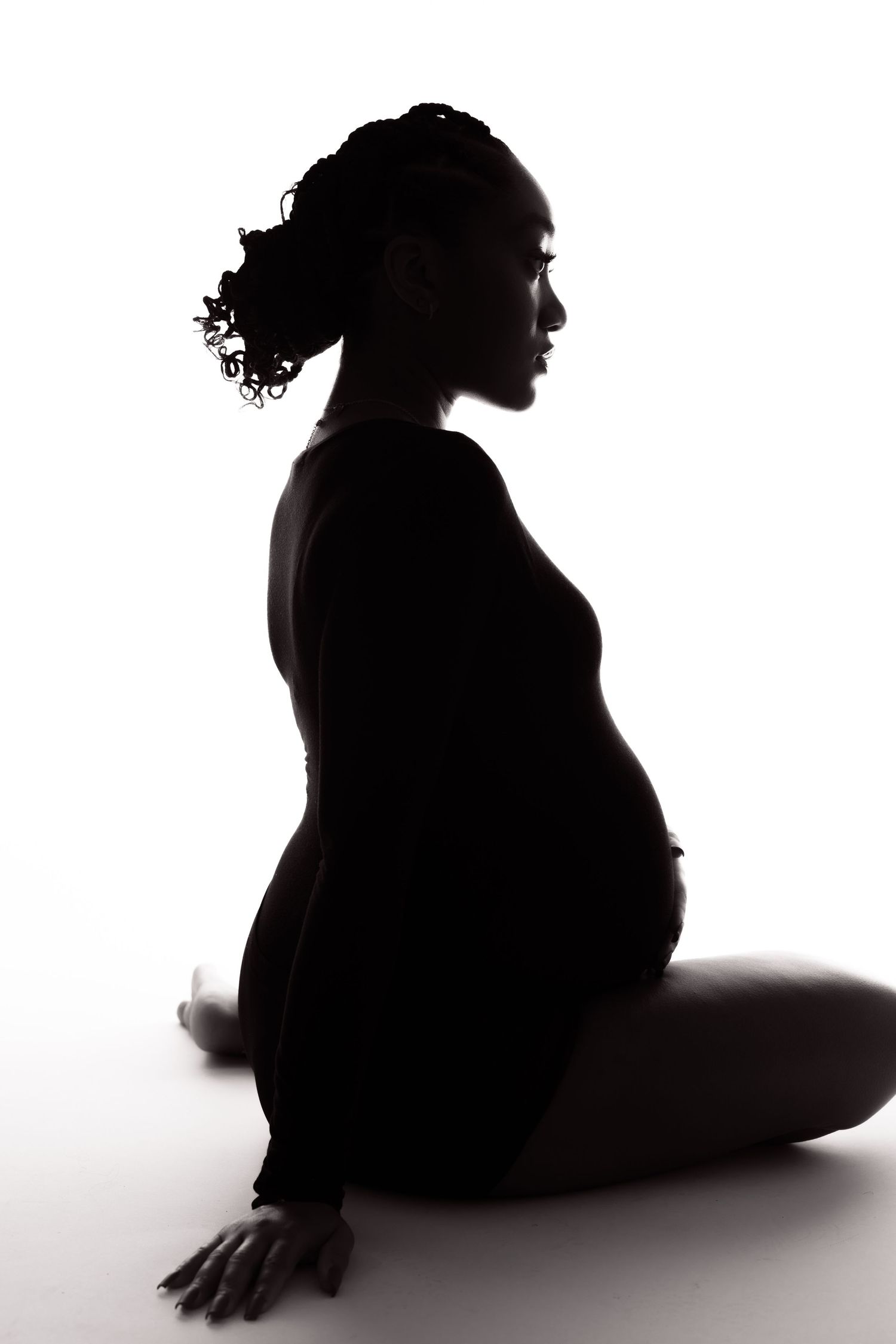 Side view silhouette of pregnant woman sitting in elegant pose.