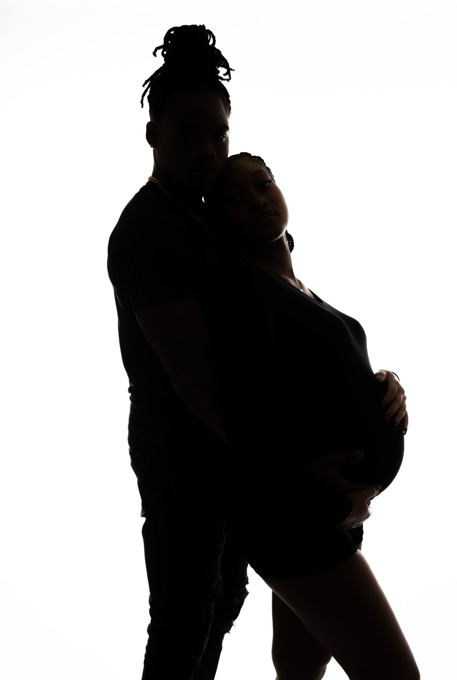 Side view silhouette of couple in loving embrace highlighting pregnant belly.