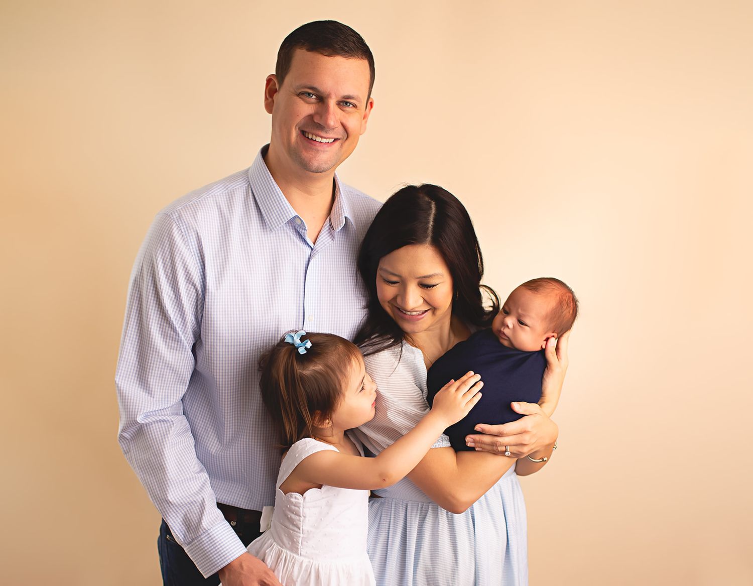 Mom, dad and big sister standing and holding newborn baby boy in Alvin, Tx photography studio