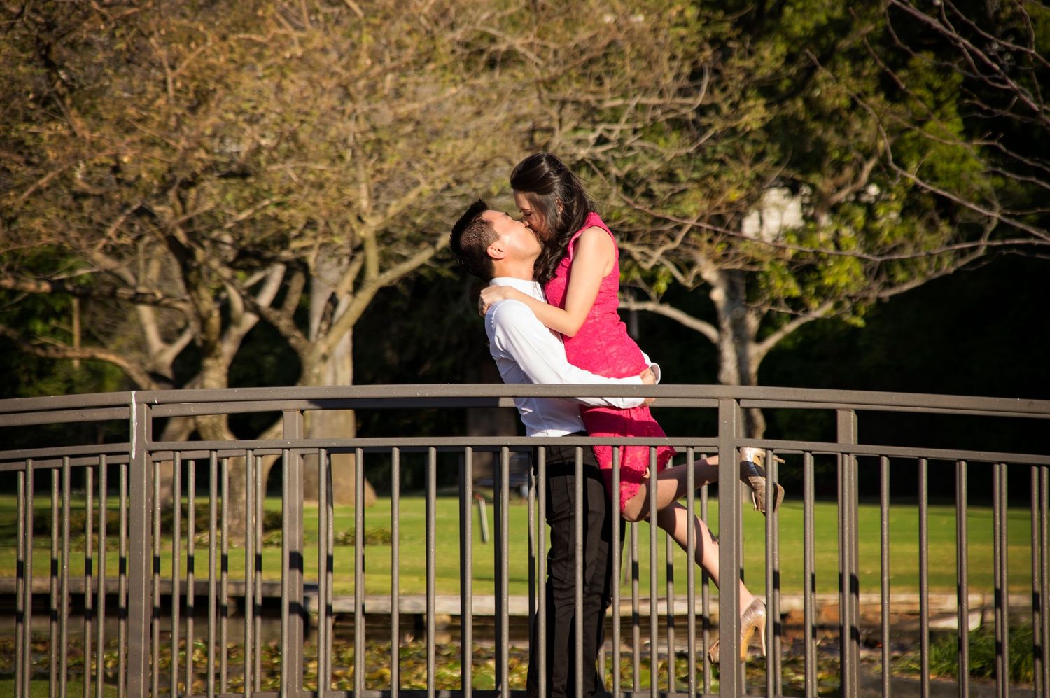 man holding up woman kissing on bridge