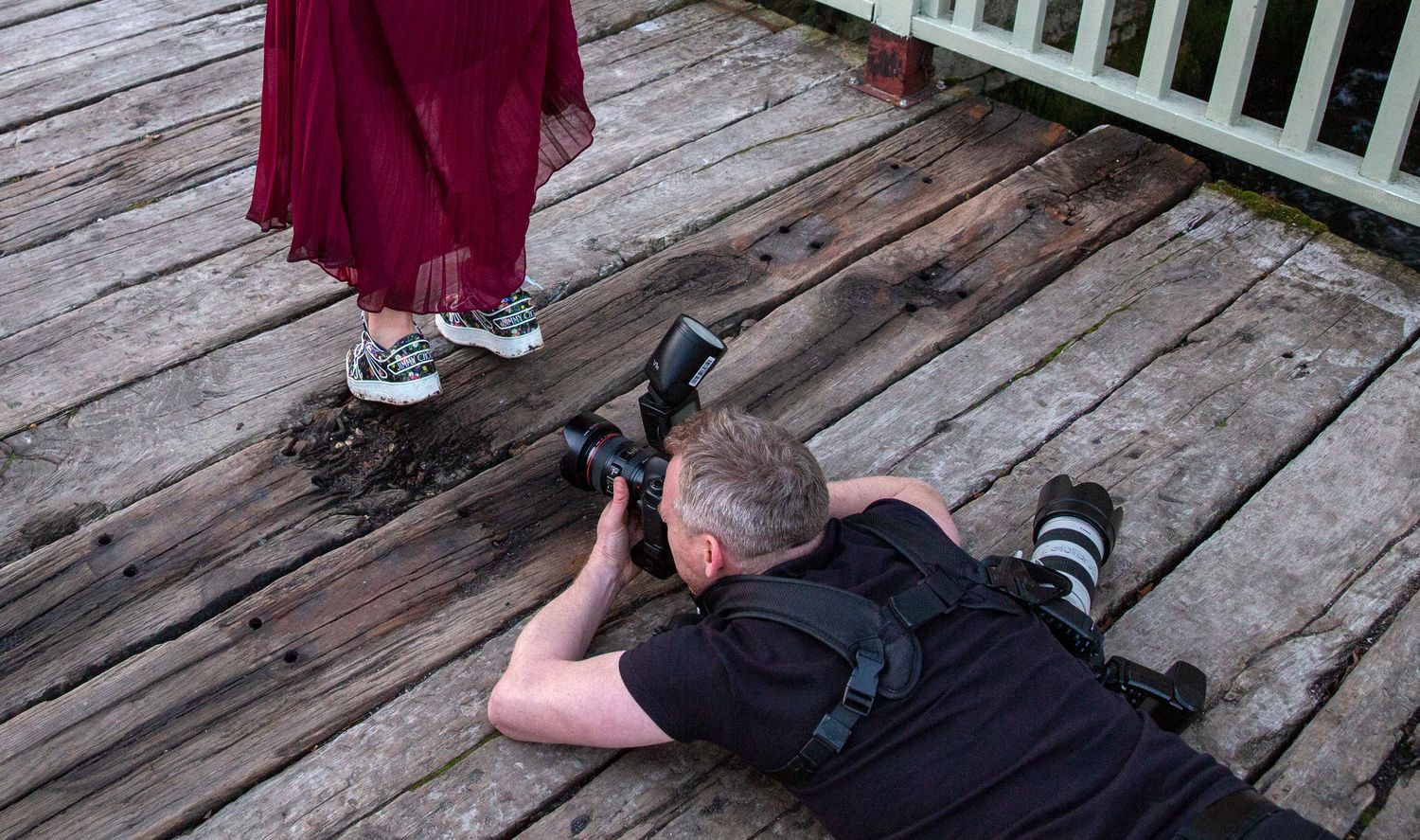 Photographer lying on wooden deck taking creative angle shots.