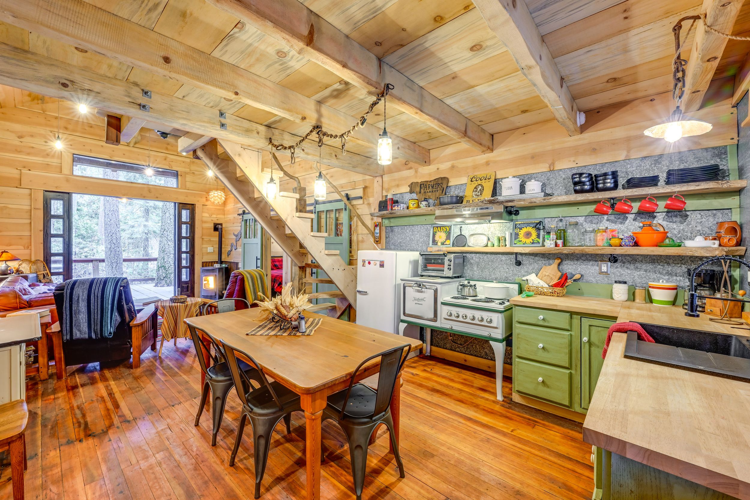 Cozy cabin kitchen with wood beams, green stove and rustic dining table.
