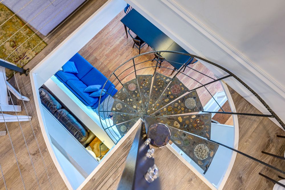 Spiral staircase viewed from above with wooden floors and blue accents.