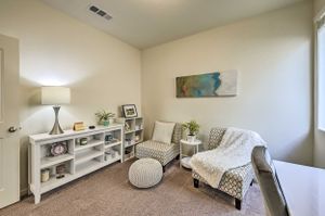 Minimalist reading nook with white shelving, gray chair and decorative accents.