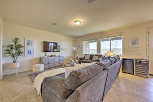 Spacious family room with gray sectional couch, TV, and large windows providing natural light.