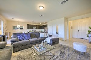 Modern living room with gray sectional sofa, blue accents, and open concept kitchen in background.