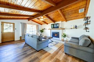 Cozy living room with vaulted wood ceiling, fireplace, and comfortable gray sofas on hardwood floors.