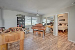 Entertainment room featuring foosball table, piano, and hardwood flooring with bedroom entrance visible.