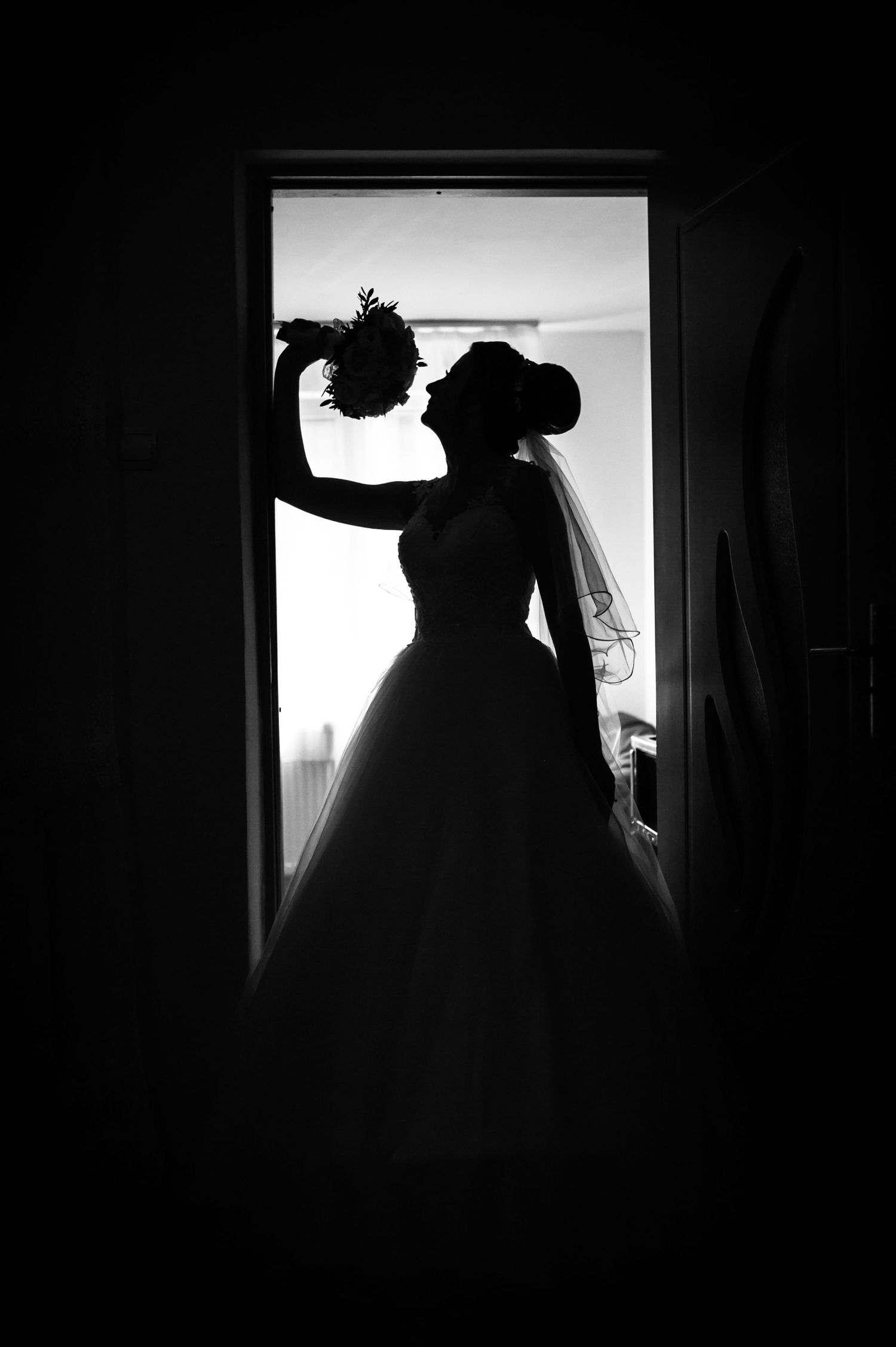 Silhouette of a bride in a wedding dress standing in a doorway highlighting her elegant gown and veil.