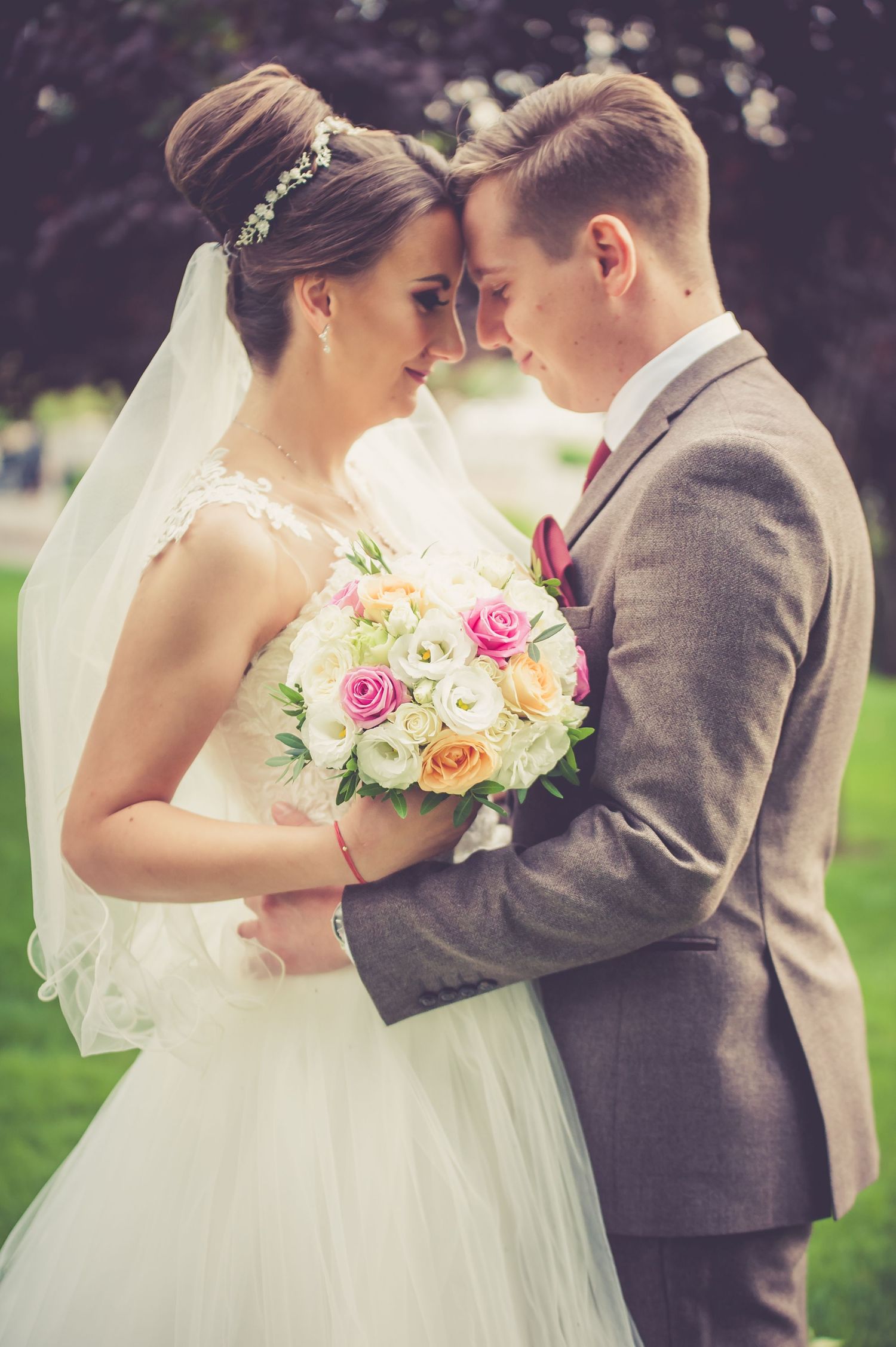 Intimate wedding portrait with bride holding floral bouquet in garden setting.